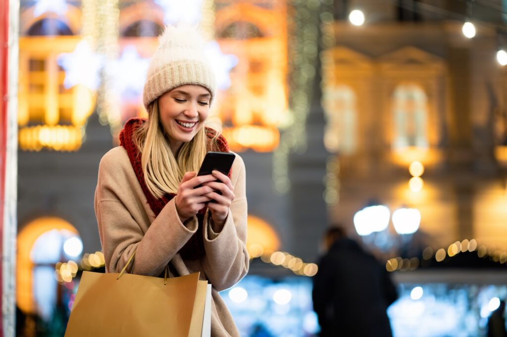Shopper woman buying online on the smart phone at Christmas. People shopping communication concept